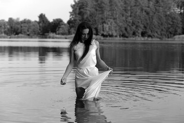 Beautiful young woman in white dress in the lake in black and white