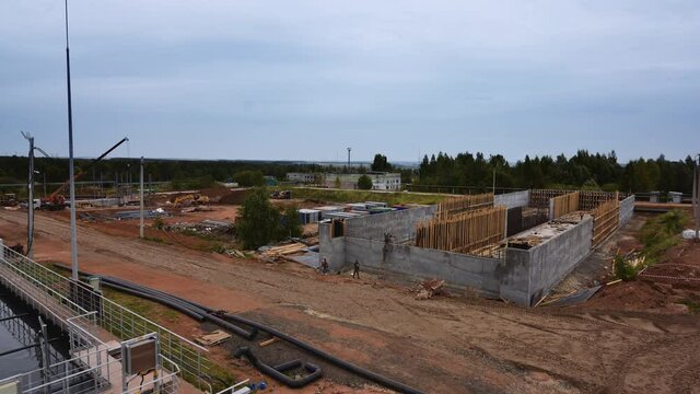 Building of large pool with machines and workers at waste water treatment plant construction site on summer day timelapse
