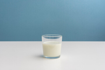 One glass of fermented milk drink, blue background, cropped image, close-up, copy space