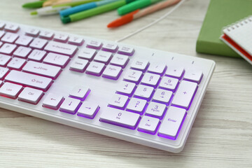 Modern RGB keyboard on white wooden table, closeup