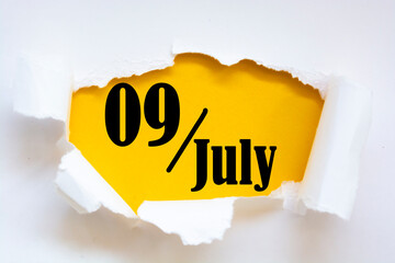 July 09. 09th day of the month, calendar date. Hole in paper with edges torn off. Yellow background is visible through ragged hole. Summer month, day of the year concept.