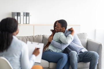 Fototapeta na wymiar Happy black couple hugging in counselor's office after successful marital therapy