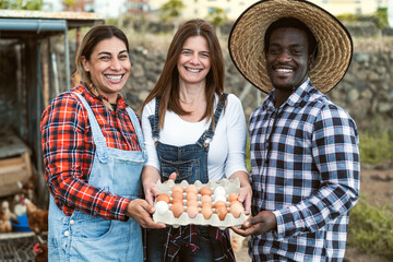 Happy farmers picking up fresh eggs in henhouse garden - Farm people lifestyle concept