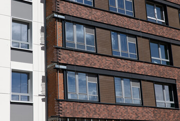 Obraz premium The facade of a residential building against a background of blue sky and greenery. Construction concept. 