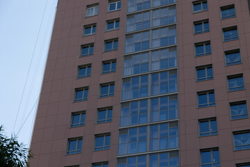 The facade of a residential building against a background of blue sky and greenery. Construction concept.
