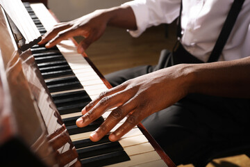 Fototapeta na wymiar African-American man playing piano indoors, closeup. Talented musician