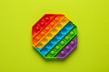 Rainbow pop it fidget toy on light green background, top view