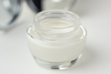 Closeup of a pampering skincare set – moisturizer in a glass jar and a mirror.