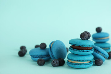 Delicious macarons and blueberries on light blue background, space for text