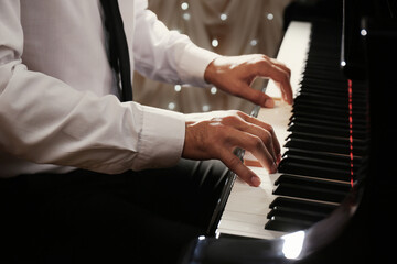 Fototapeta na wymiar Man playing piano indoors, closeup. Talented musician