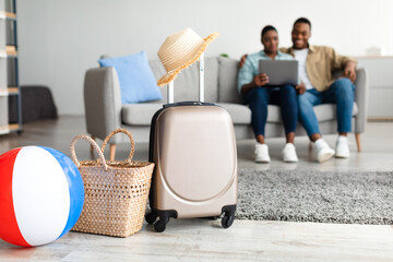 African American Family Using Laptop While Packed Suitcase Lying Indoor