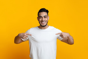 Excited arab guy pointing at his blank white t-shirt