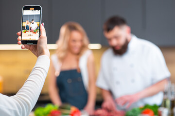 Young woman and man prepare food and host a cooking show. The bloggers stream from modern kitchen. Healthy food preparation.