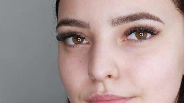 Young beautiful healthy girl model posing in the salon, smiling and rejoicing in front of the camera. Face without makeup, with long eyelash extensions before applying makeup. Close up
