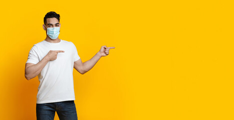 Arab guy in face mask pointing at copy space