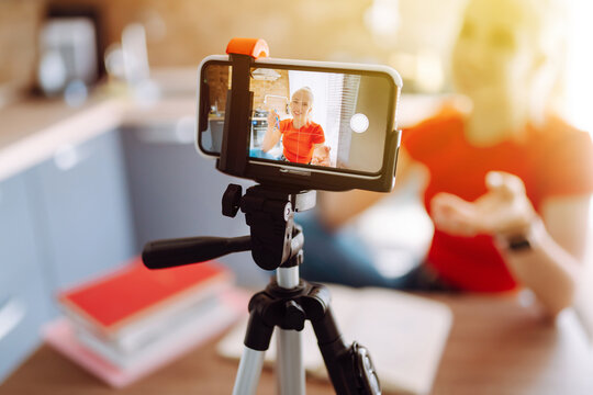 Young woman recording her video blog. Woman blogger videotapes her vlog at home. Vlogger makes online streaming using phone. Social media, instagram, stay home and quarantine.