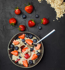 The concept of a healthy breakfast of oatmeal with strawberries and blueberries