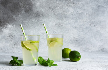 Fototapeta premium Iced tea with lime. Cold lemonade with lime on a concrete background.