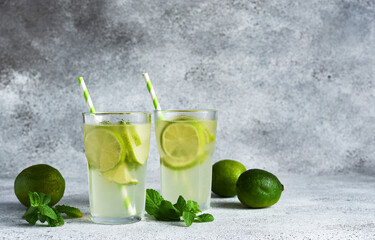 Iced tea with lime. Cold lemonade with lime on a concrete background.