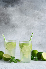 Iced tea with lime. Cold lemonade with lime on a concrete background.