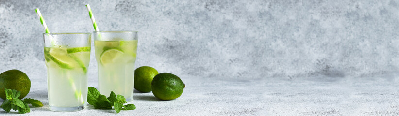 Iced tea with lime. Cold lemonade with lime on a concrete background.