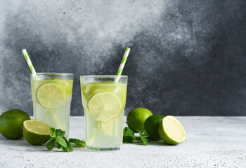 Iced tea with lime. Cold lemonade with lime on a concrete background.