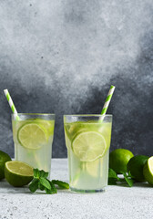 Fototapeta premium Iced tea with lime. Cold lemonade with lime on a concrete background.