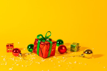 Gift box with a Christmas present on a yellow background, among the New Year's decorations