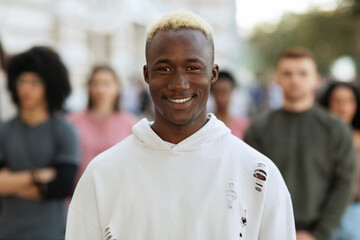Cheerful young black guy standing over multiracial crowd