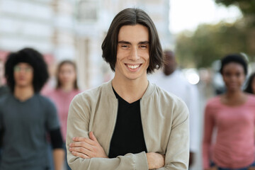 Cheerful young man standing over multiracial crowd on street