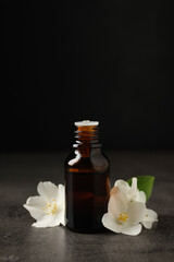 Essential oil and jasmine flowers on grey table