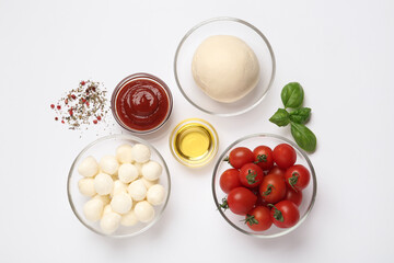 Raw dough and other ingredients for pizza on white background, top view