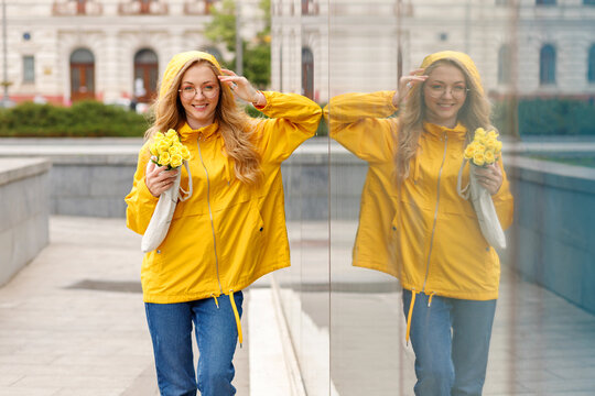 Woman in bright yellow raincoat with eco bag in the city on a walk in the rain