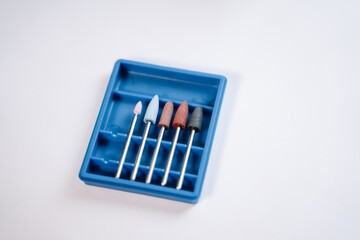 On a white table is a box with attachments (cutters) for a manicure machine.