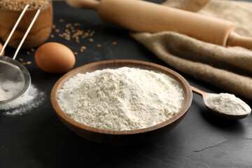 Wooden bowl of flour on black table