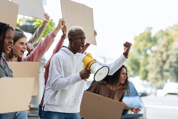 Side view of multiracial people with blank placards chanting slogans