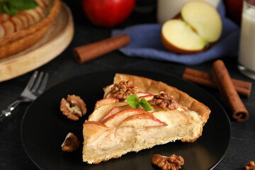 Slice of delicious apple pie on black table