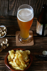 Cerveza artesanal sobre una mesa junto a unos pistachos para picar