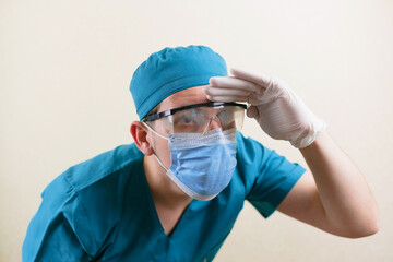 Seartchong doctor in blue surgeon suit and glasses looking into distance on the yellow background...