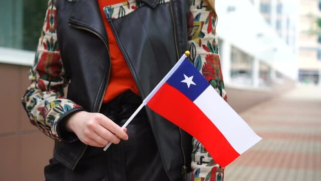Unrecognizable woman holding Chilean flag. Girl walking down street with national flag of Chile