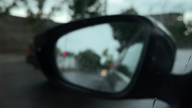 Blurred image background, close-up view of city life through car mirror.