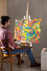 Male artist working on painting. Man artist painter in creative studio
