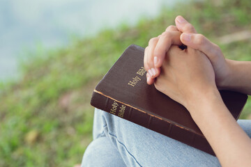 Hands of a woman on the bible. she is reading and praying over bible in garden Concepts of...