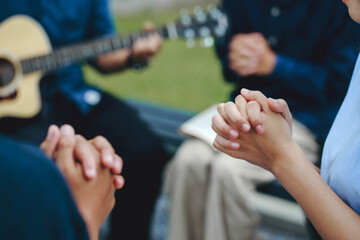 Christian families worship God in the garden by playing guitar and holding a holy bible. Group...