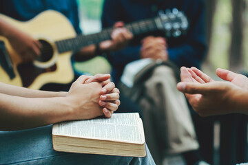 Christian families worship God in the garden by playing guitar and holding a holy bible. Group Christianity people reading the bible together.Concept of wisdom, religion, reading, imagination. - obrazy, fototapety, plakaty