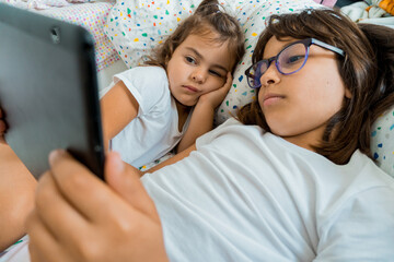 Two girls lying on their beds with a tablet.