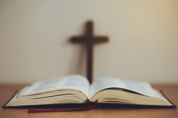 close up of open bible with cross on wooden table with window light.The concept of Bible learning and faith in God.