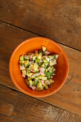 Okroshka in a clay bowl on a table on a wooden table.