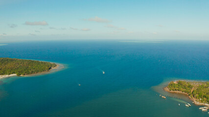 Tropical island Balabac covered with green rain forest against the blue sky with clouds and blue sea from above. Seascape: Ocean and sky. Palawan, Philippines