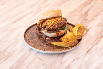 Butcher's burger with a good piece of meat covered with barbecue sauce with crunchy onion and potato wedges garnish